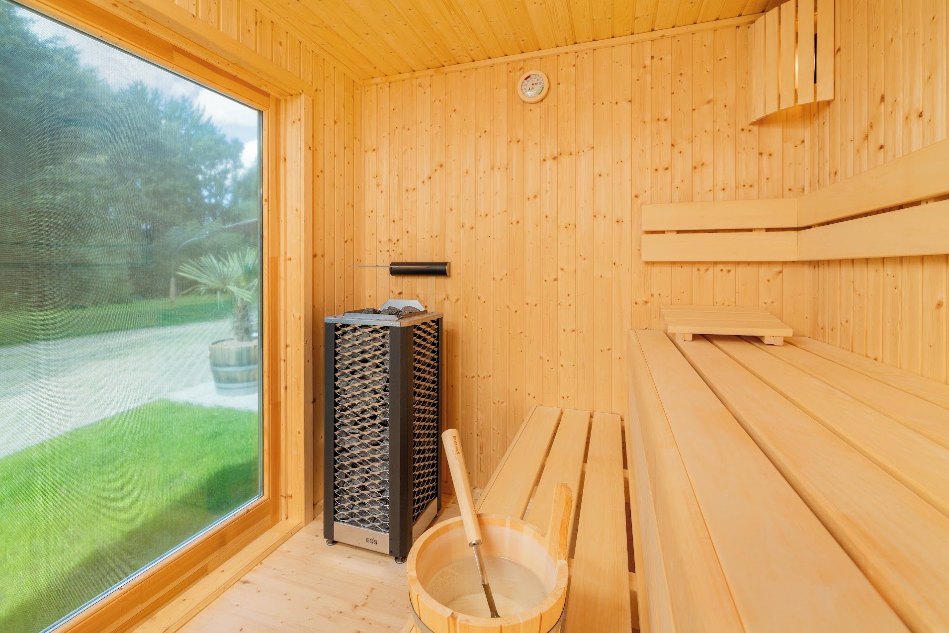 Een sauna met houten wanden, een bankje, een emmer en een sauna-oven.