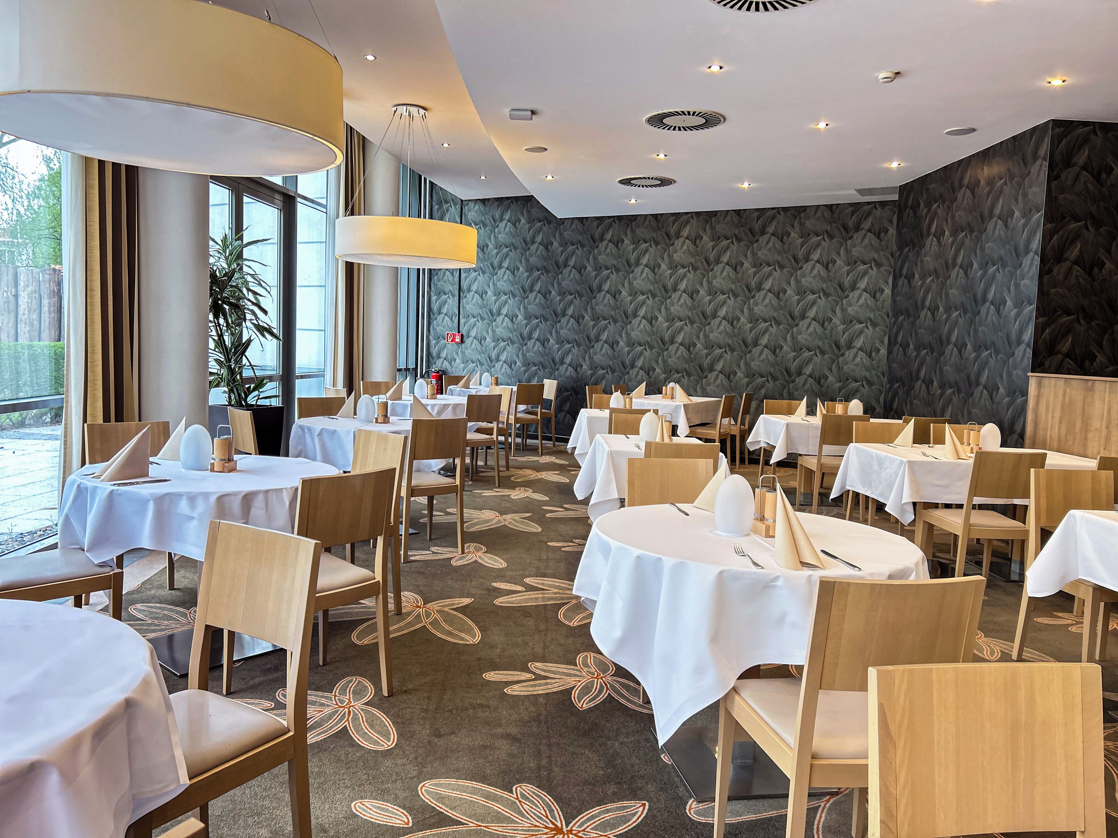 En restaurang med runda bord, trästolar och en mönstrad matta.