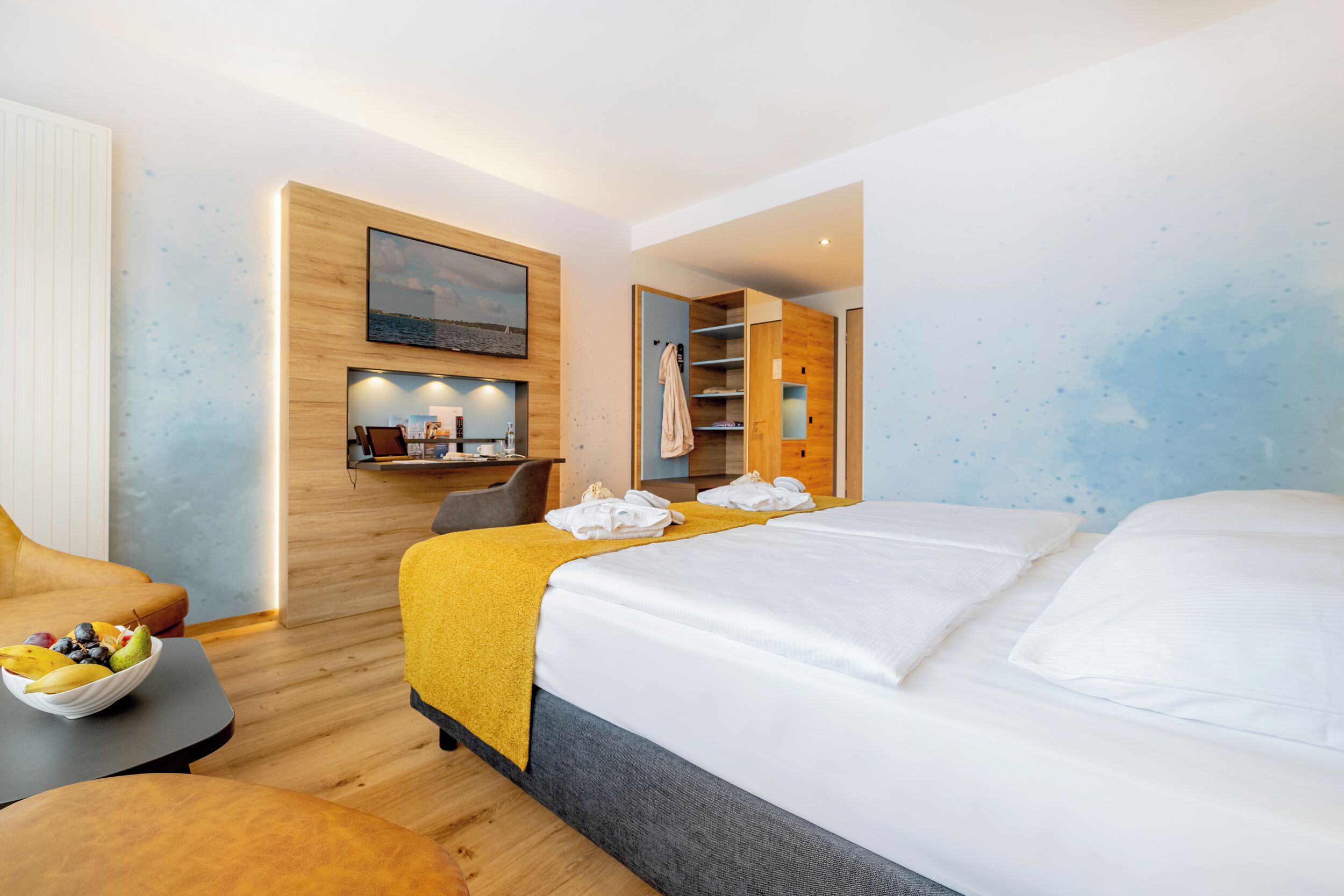 Moderni hotellihuone, jossa on sänky, työpöytä ja oleskelualue.
