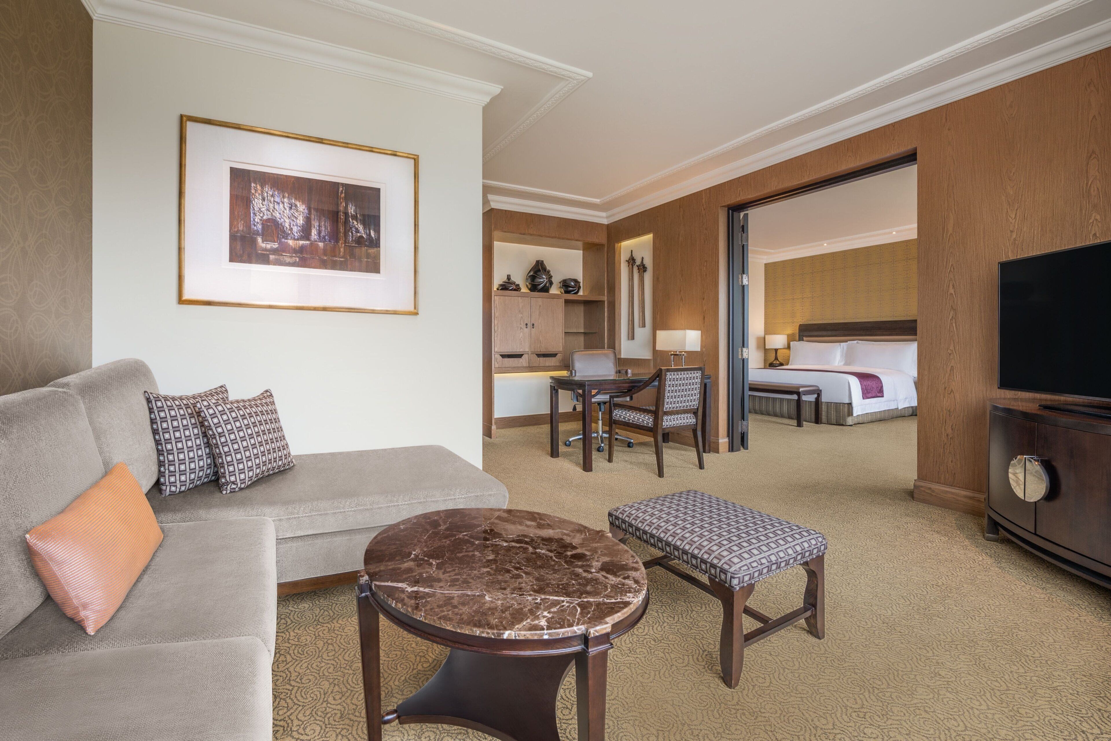Habitación de hotel con sofá, una mesita redonda, una silla, cama, televisor y zona de cocina.