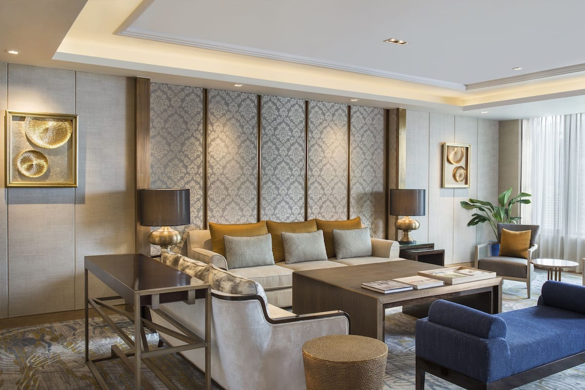 A modern hotel room with a sofa set, a coffee table, a side table, and a lamp.