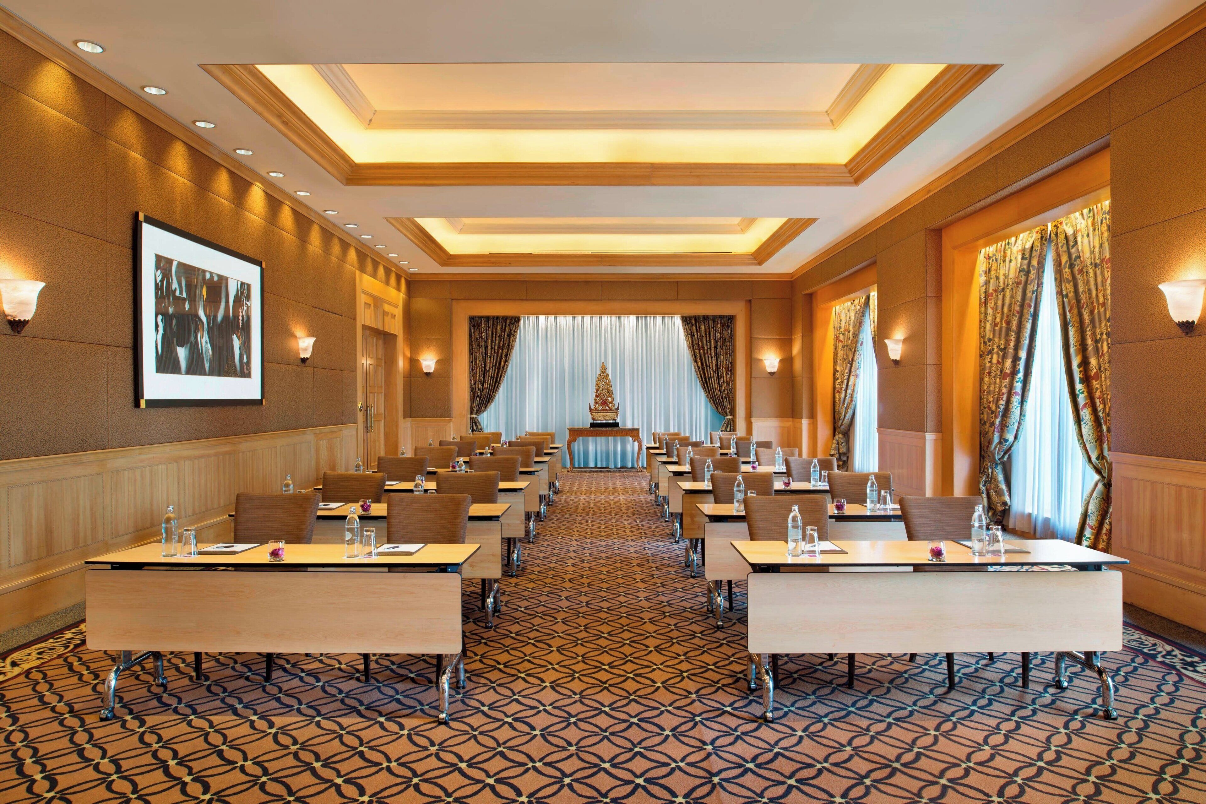 A conference room with long tables, chairs, and a patterned carpet.