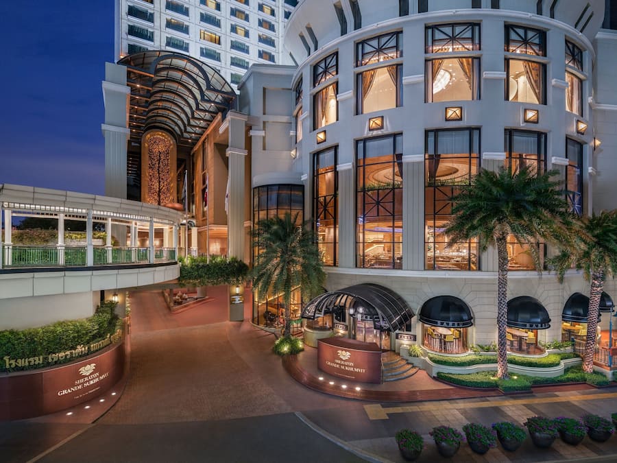 A grand hotel with a curved facade, multiple balconies, and a well-lit entrance area.