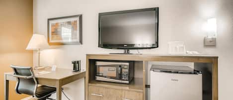 Habitació d'hotel amb escriptori, cadira, televisió de pantalla plana, microones, nevera i un quadre al mur.