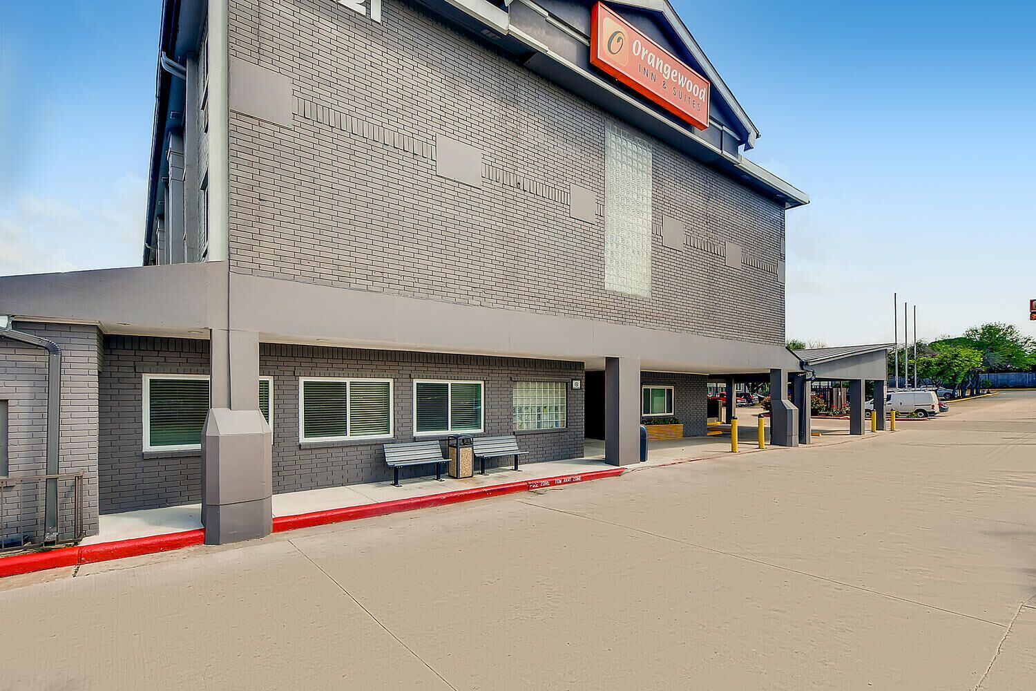 A hotel with a modern brick facade, outdoor seating area, and a clear sky.