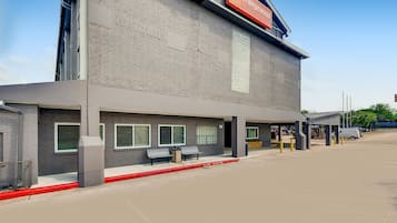 A hotel with a modern brick facade, outdoor seating area, and a clear sky.