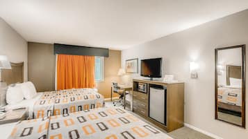 Habitación de hotel con dos camas, un escritorio, un televisor y un refrigerador.