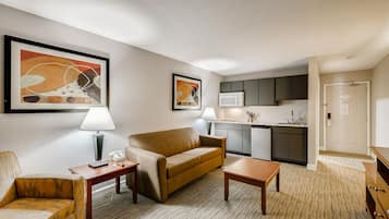 Habitación de hotel con sofá, sillón, mesa de centro y un área de kitchenette.