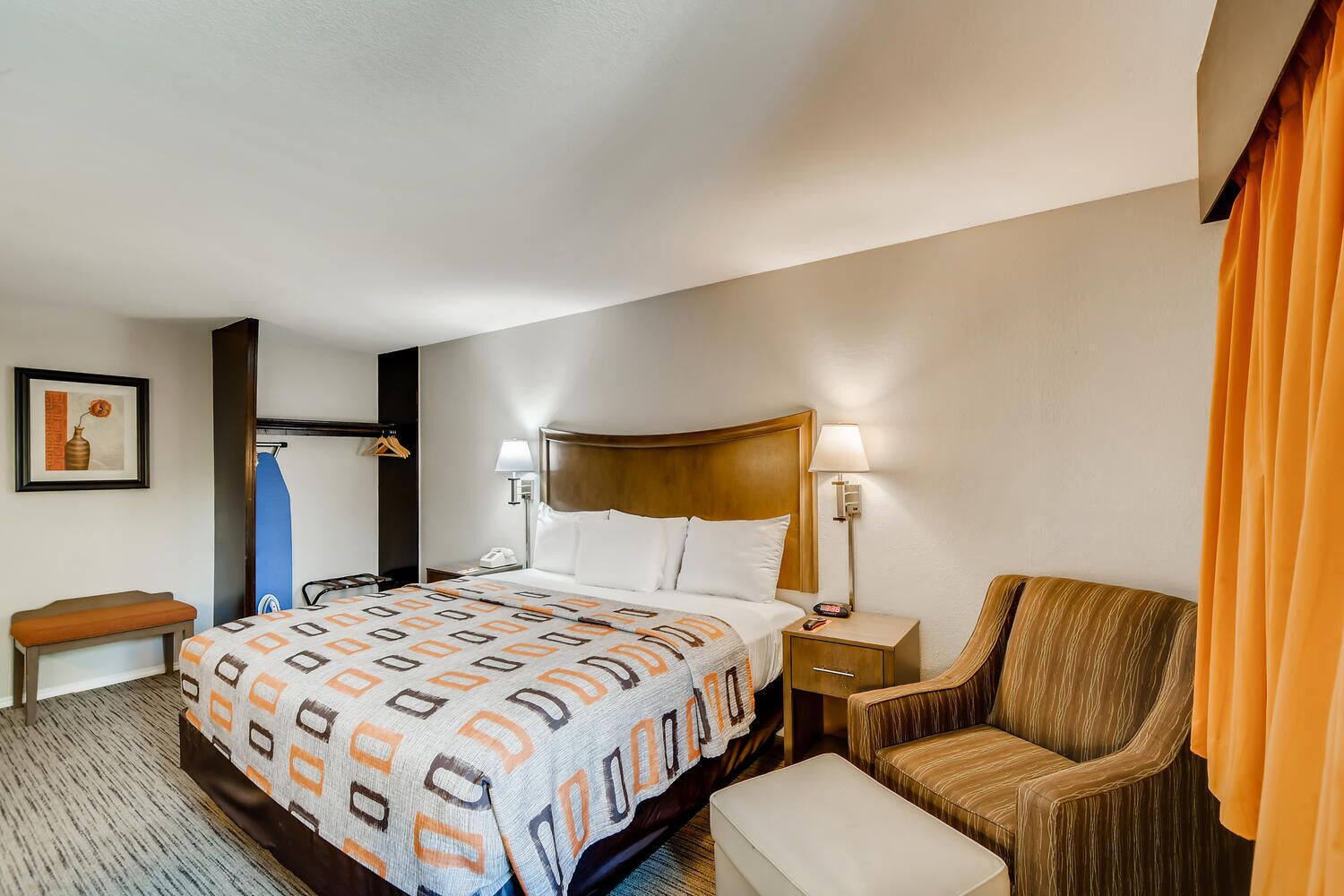 Una camera d'albergo con un letto grande, un comodino, una sedia e un tavolino.