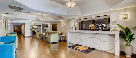 A hotel reception area with a marble counter, a fitness center sign, and a reception desk.