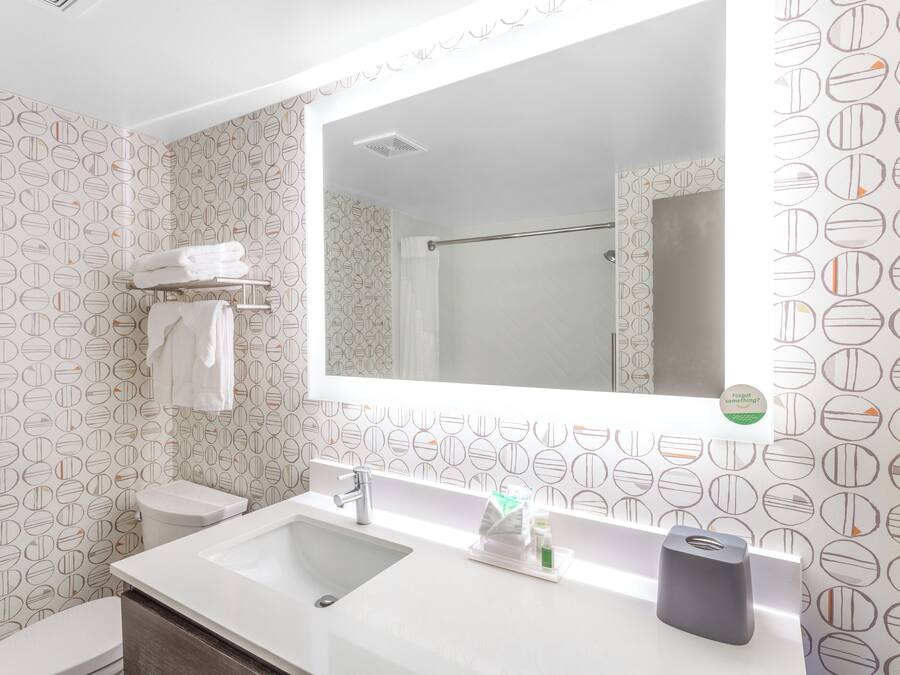 A bathroom with a white sink, a mirror, a towel rack, and a toilet.