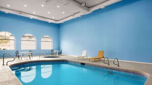 An indoor swimming pool with clear blue water, surrounded by lounge chairs and tables. - Days Inn by Wyndham Ruidoso Downs (Ruidoso Downs)