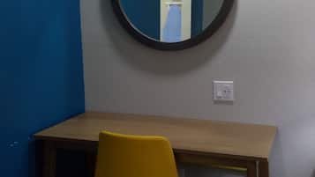 Una habitación con un escritorio de madera, una silla de oficina amarilla y un espejo redondo en la pared.