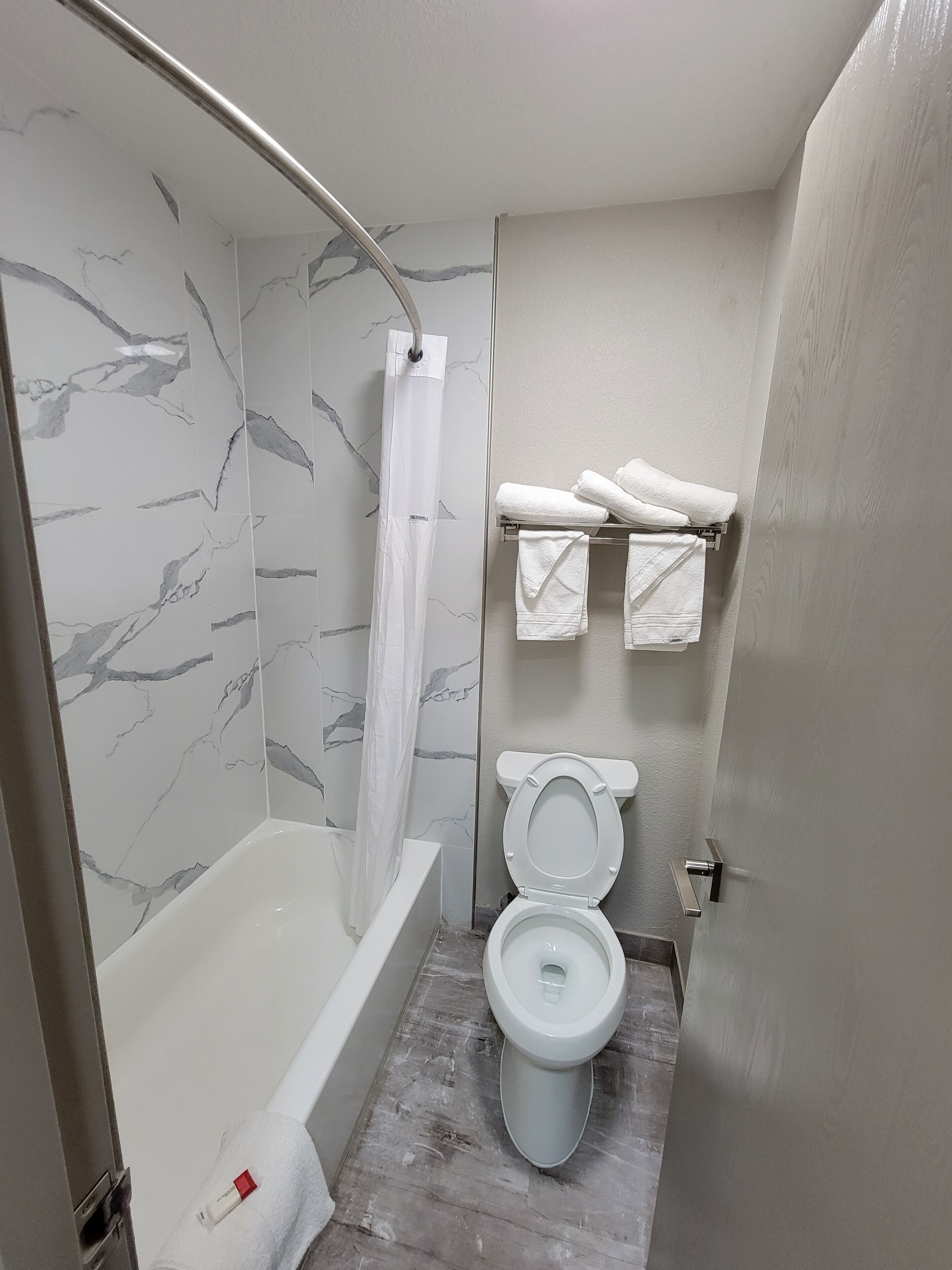 Une salle de bain avec une baignoire, des toilettes et un rideau de douche.