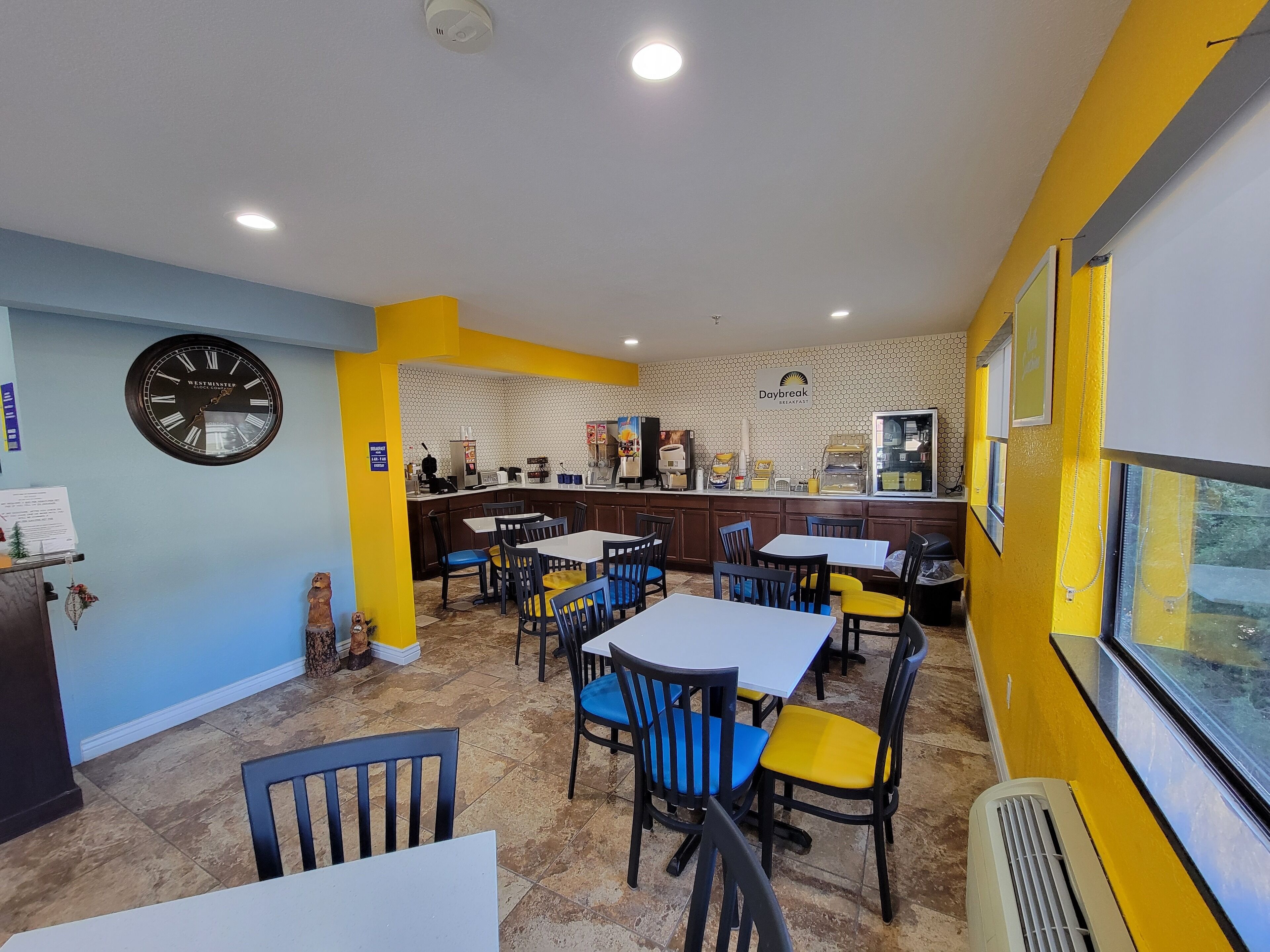 A restaurant with a clock, tables, chairs, and a counter.