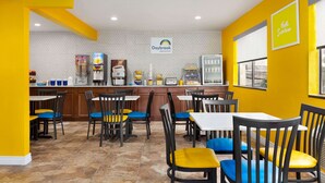 A breakfast area with yellow walls, a hexagonal tile backsplash, and a sign reading "Daybreak Breakfast". There are tables and chairs with blue and yellow cushions. - Days Inn by Wyndham Ruidoso Downs (Ruidoso Downs)