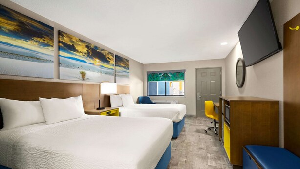 A hotel room with two beds, a desk, a chair, a television, and artwork on the walls. - Days Inn by Wyndham Ruidoso Downs (Ruidoso Downs)