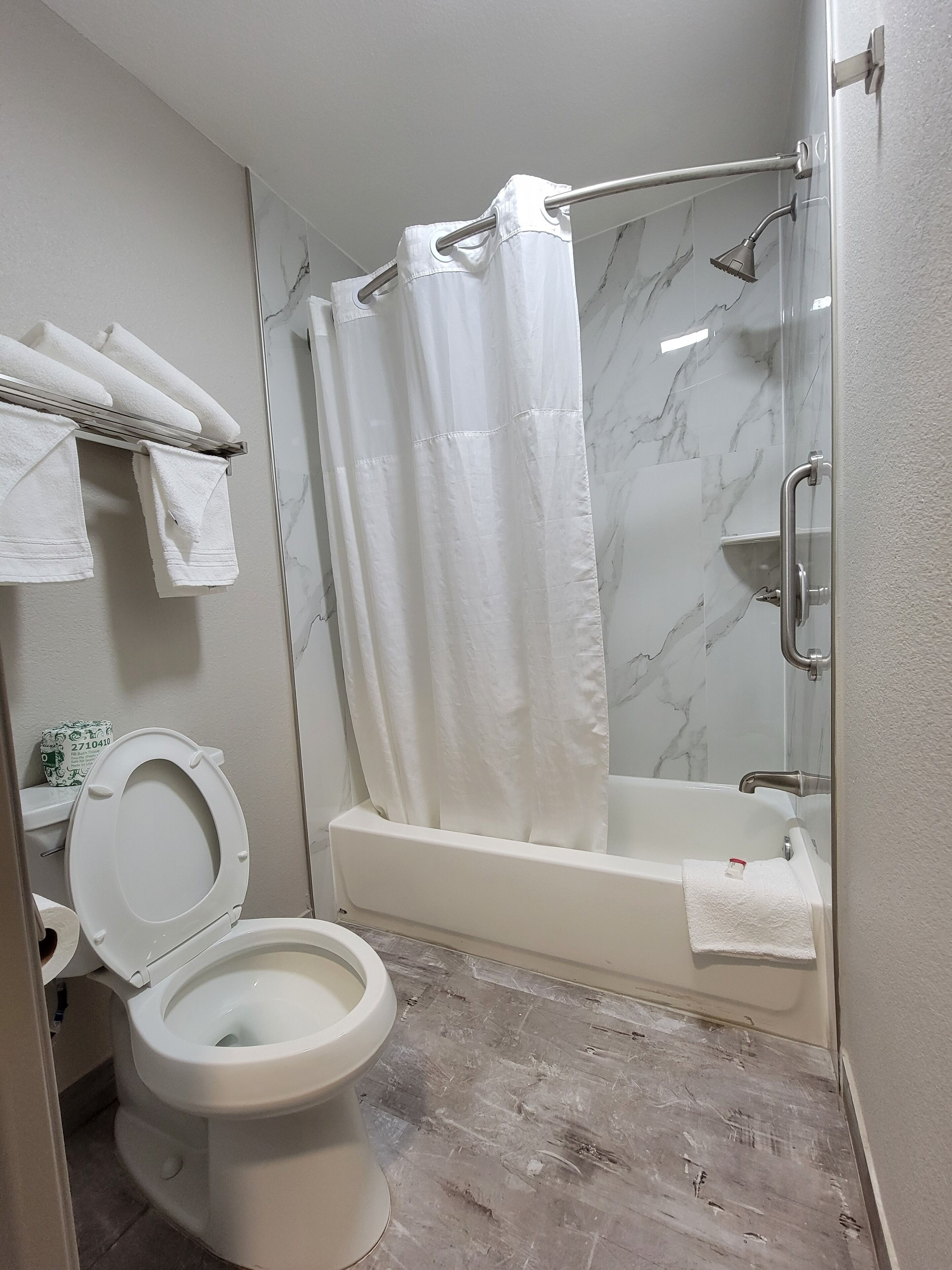 Een badkamer met een toilet, een douche met glazen deur en een bad.