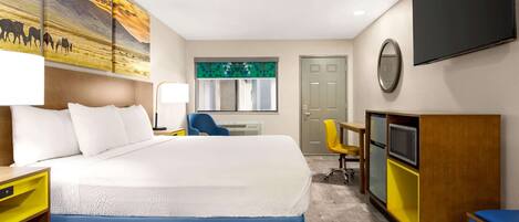 A hotel room with a large bed, a desk, a chair, a TV, and a painting on the wall.