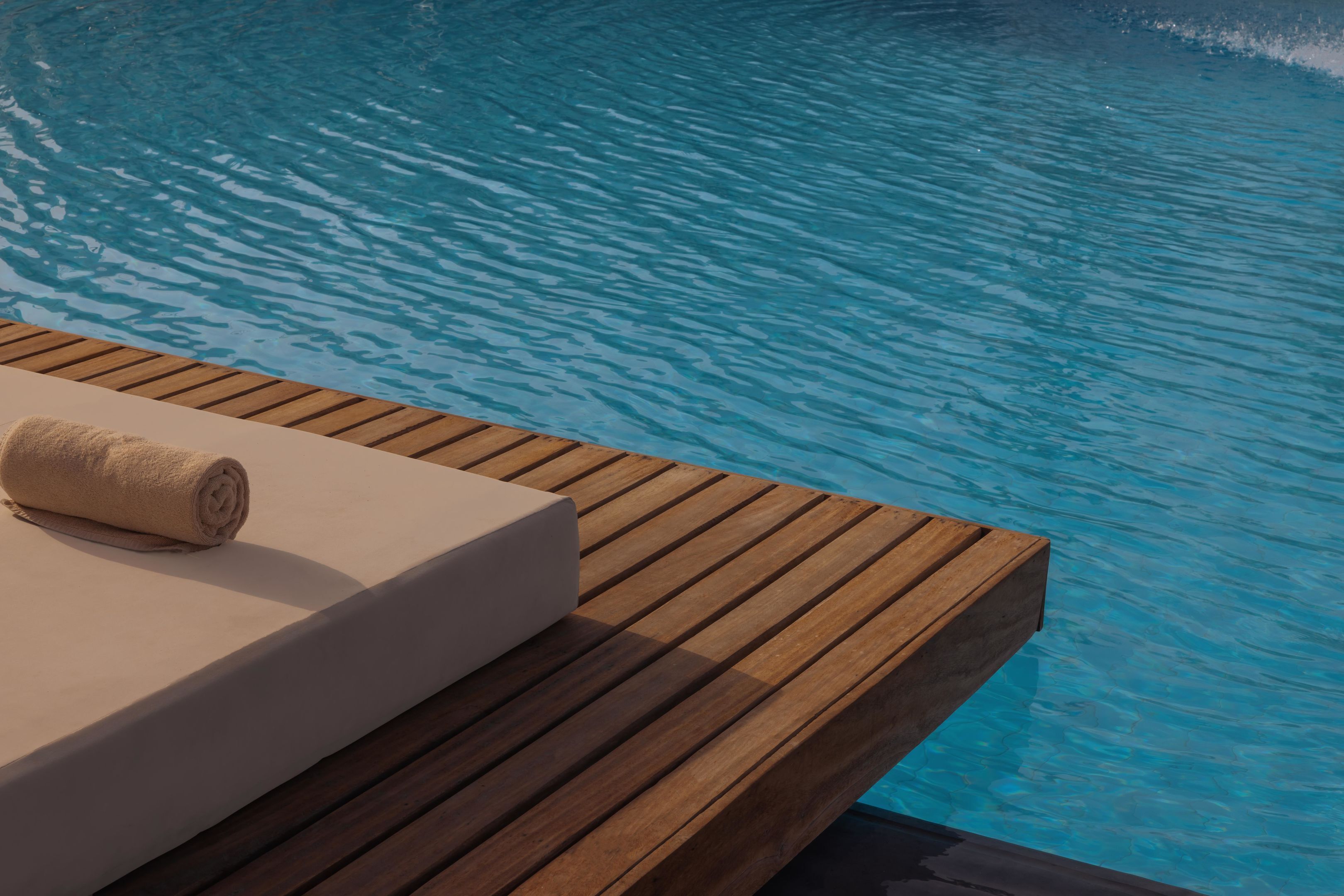 Una terraza de madera con un sofá blanco y una toalla enrollada.