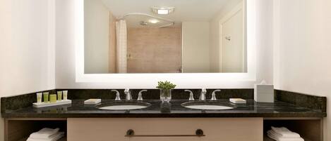 A modern bathroom with two sinks, a large mirror, and a towel rack.