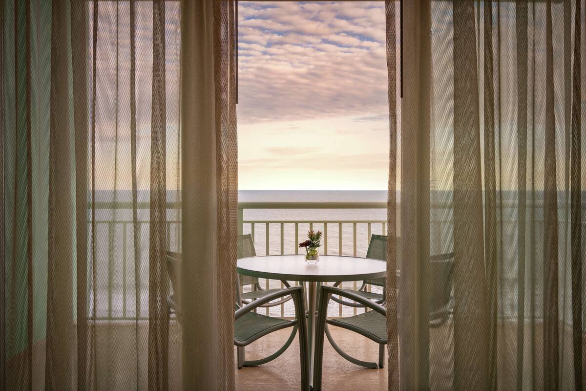 Un balcon avec une table et des chaises, donnant sur une étendue d’eau.