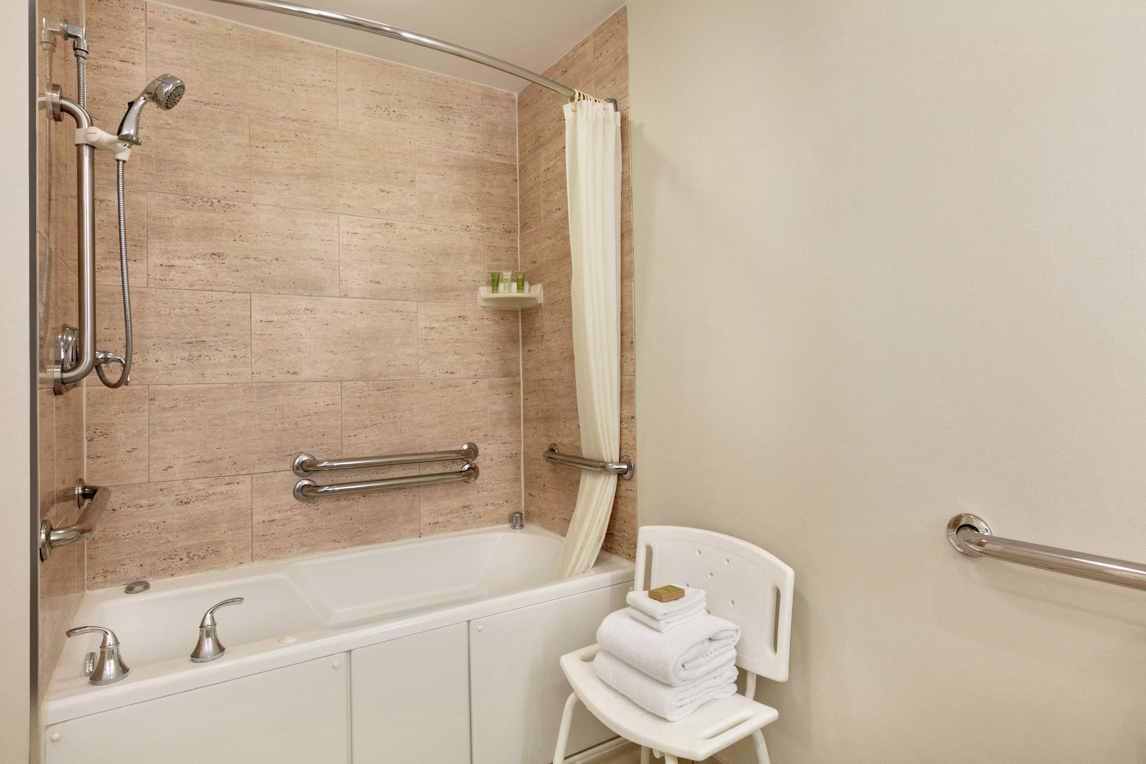 Un baño moderno con bañera, ducha y barras de apoyo.