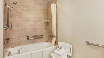 Un baño moderno con bañera, ducha y barras de apoyo.