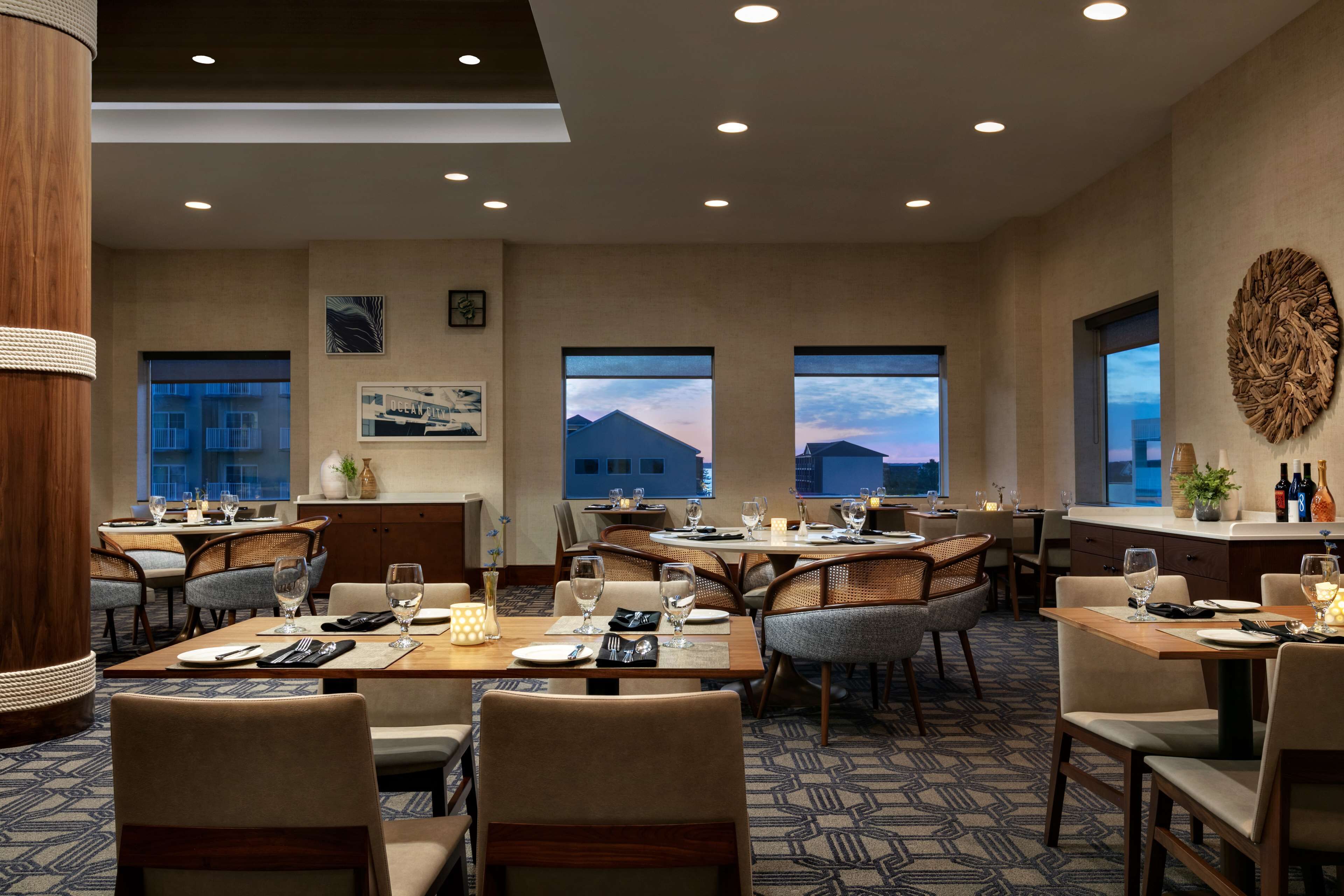 A spacious dining area with multiple tables and chairs, large windows with mountain views, and a modern ceiling design.