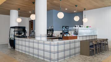 A modern bar area with a checkered floor, a counter with a coffee machine, and pendant lighting.
