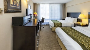 A hotel room with a bed, a desk, a television, a lamp, and a window with curtains. - Comfort Inn & Suites Edmonton Downtown (Edmonton)
