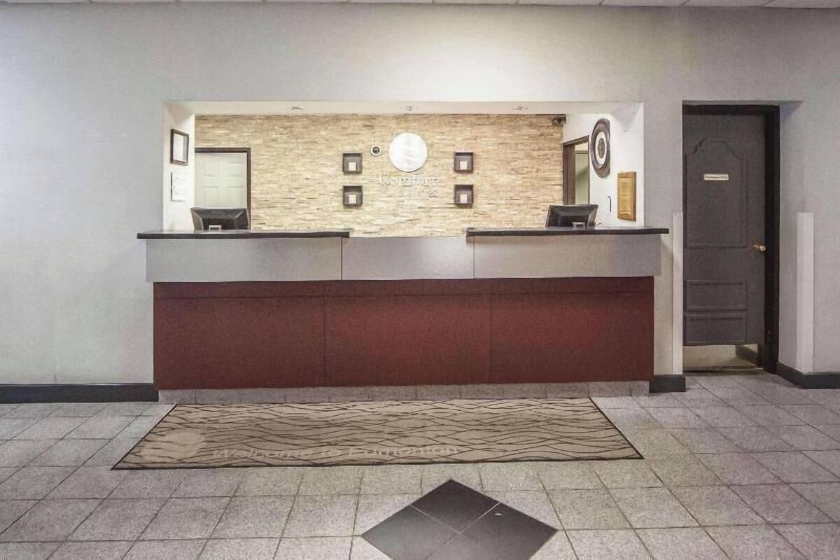 Un mostrador de recepción con un fondo de pared de piedra, una encimera de color oscuro y una alfombra estampada en el suelo.