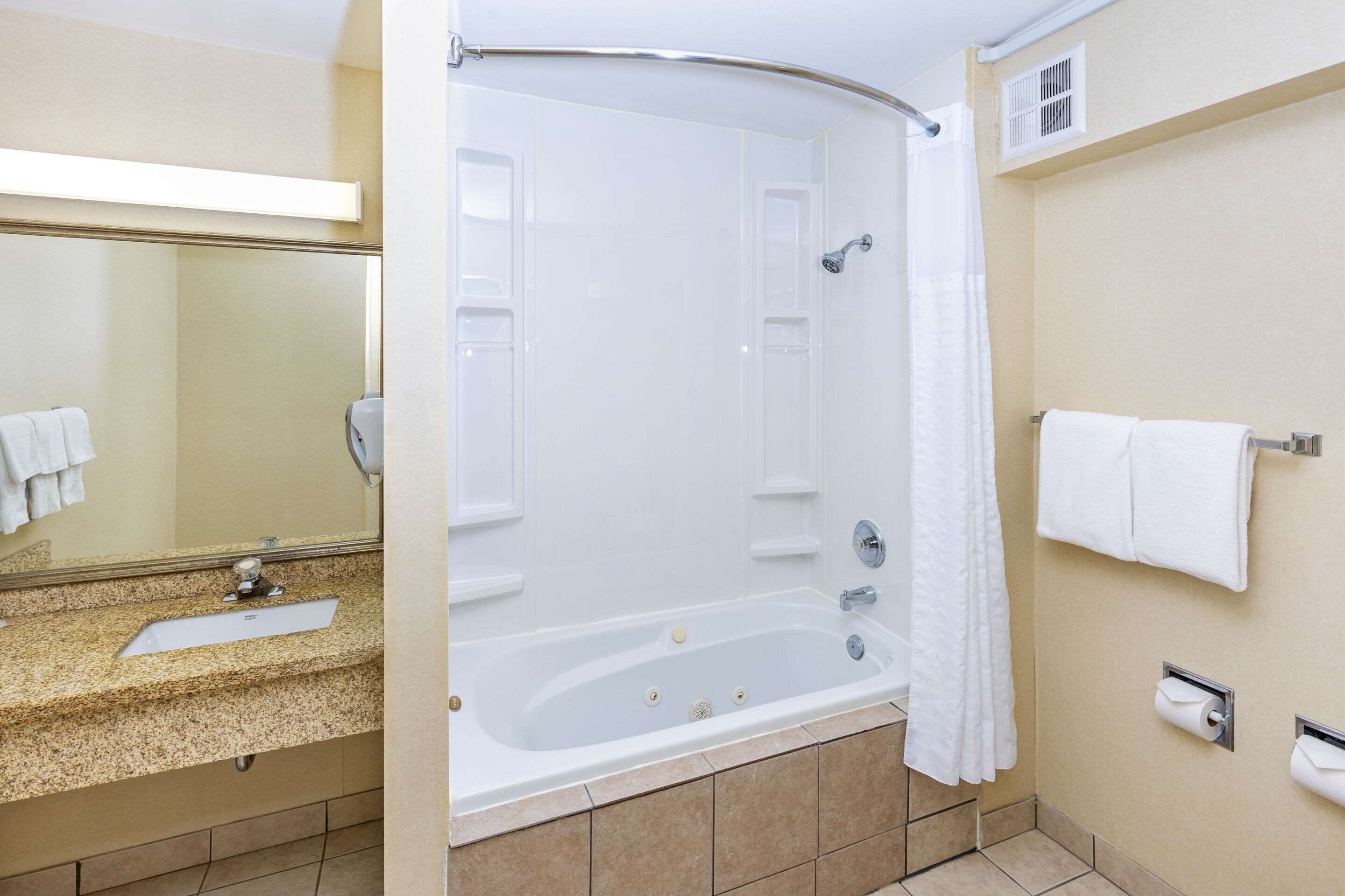 Une salle de bain moderne équipée d’une baignoire, d’un lavabo, d’un miroir et d’un porte-serviettes.