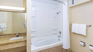 Une salle de bain moderne équipée d’une baignoire, d’un lavabo, d’un miroir et d’un porte-serviettes.