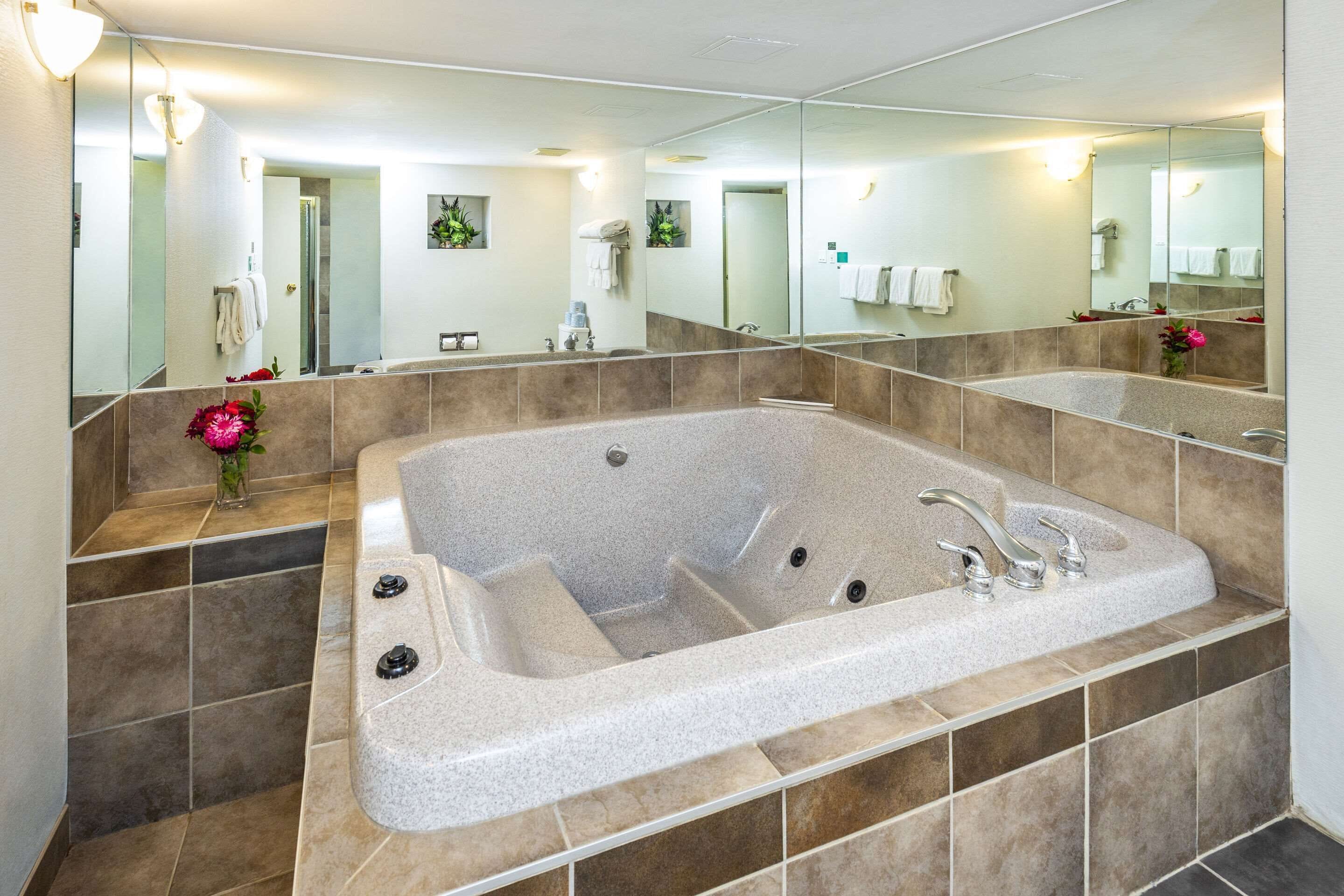 A modern bathroom with a large freestanding bathtub, a large mirror, and a vanity with a sink.