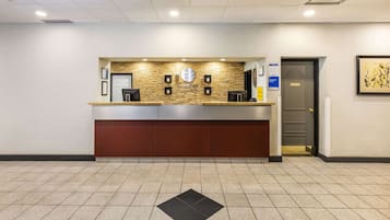 Un mostrador de recepción con un fondo de pared de piedra, un reloj y una puerta a la derecha.
