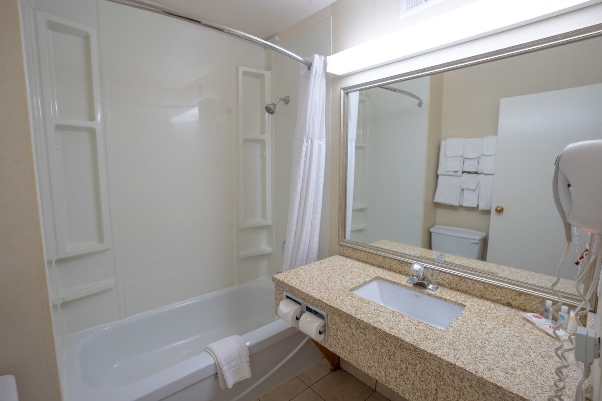 Un baño con bañera, lavamanos, espejo y perchero para toallas.