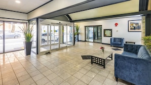 A lobby with a tiled floor, a reception desk, a blue sofa, and a potted plant. - Comfort Inn & Suites Edmonton Downtown (Edmonton)