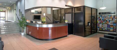 A reception area with a curved counter, a potted plant, and a wall with brochures.