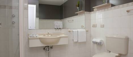 Un baño moderno con lavamanos, espejo, inodoro y ducha.