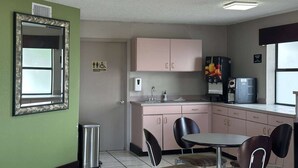 A small kitchenette with a sink, cabinets, and a refrigerator. There is a trash can and a window with blinds. - Super 8 by Wyndham Monroe (Monroe)