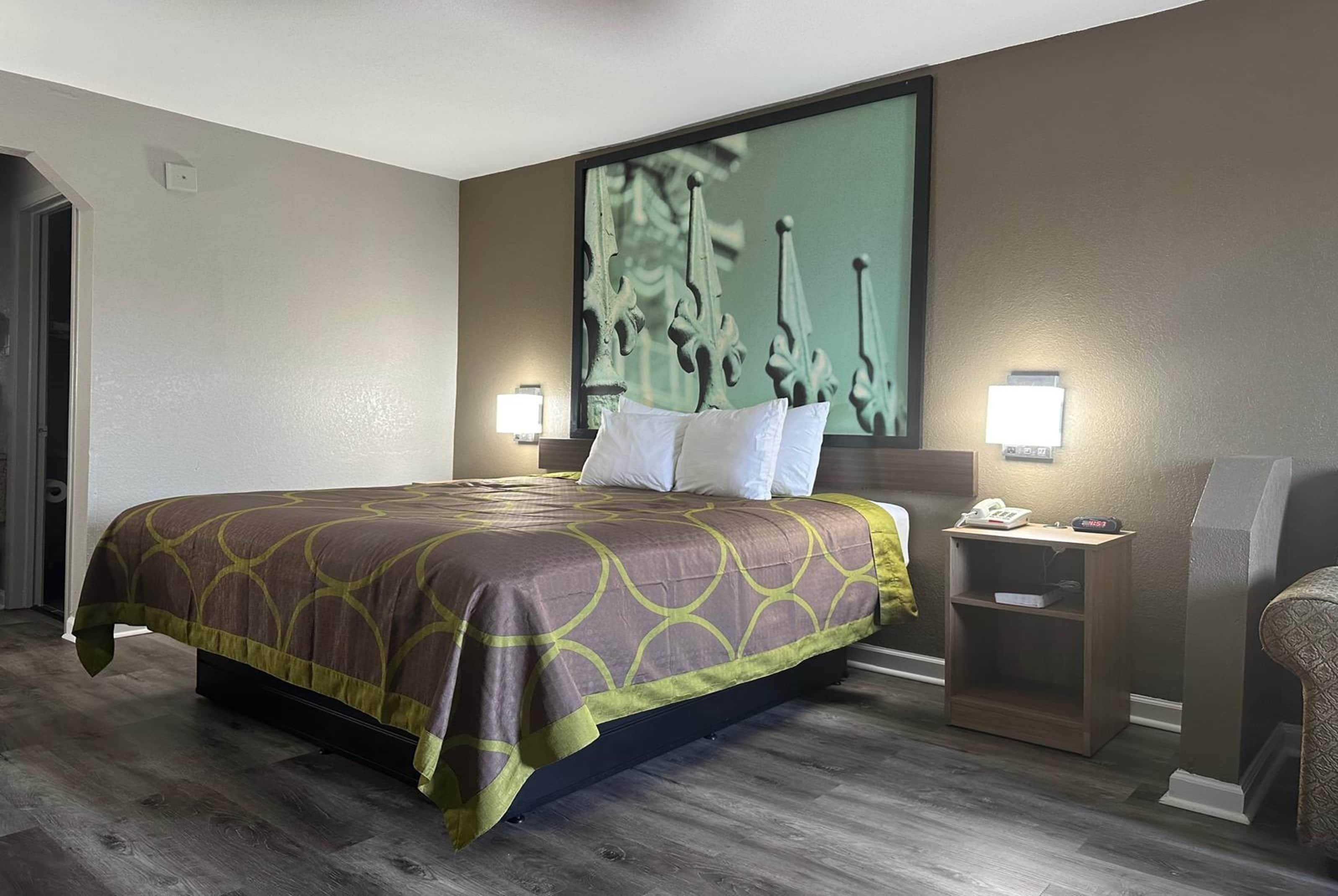 A hotel room with a large bed, two bedside tables, a nightstand, and a wall-mounted TV.