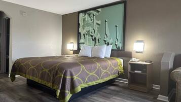 A hotel room with a large bed, two bedside tables, a nightstand, and a wall-mounted TV.