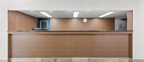 A reception desk with a modern design, featuring horizontal wooden slats and a digital clock above it.