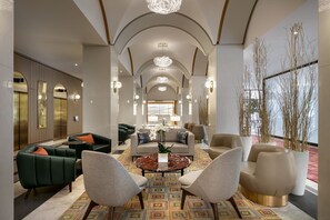 Experience a blend of contemporary and classic style in our elegantly designed lobby, featuring a central seating area with sofas and armchairs.