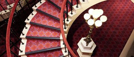 A spiral staircase with red carpeted steps and black railings.