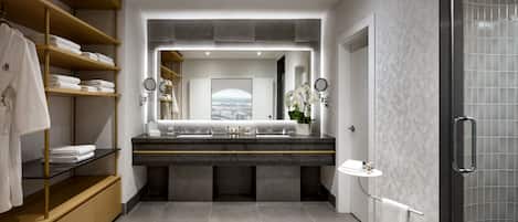 A modern bathroom with a large mirror, dual sinks, and a shower area.