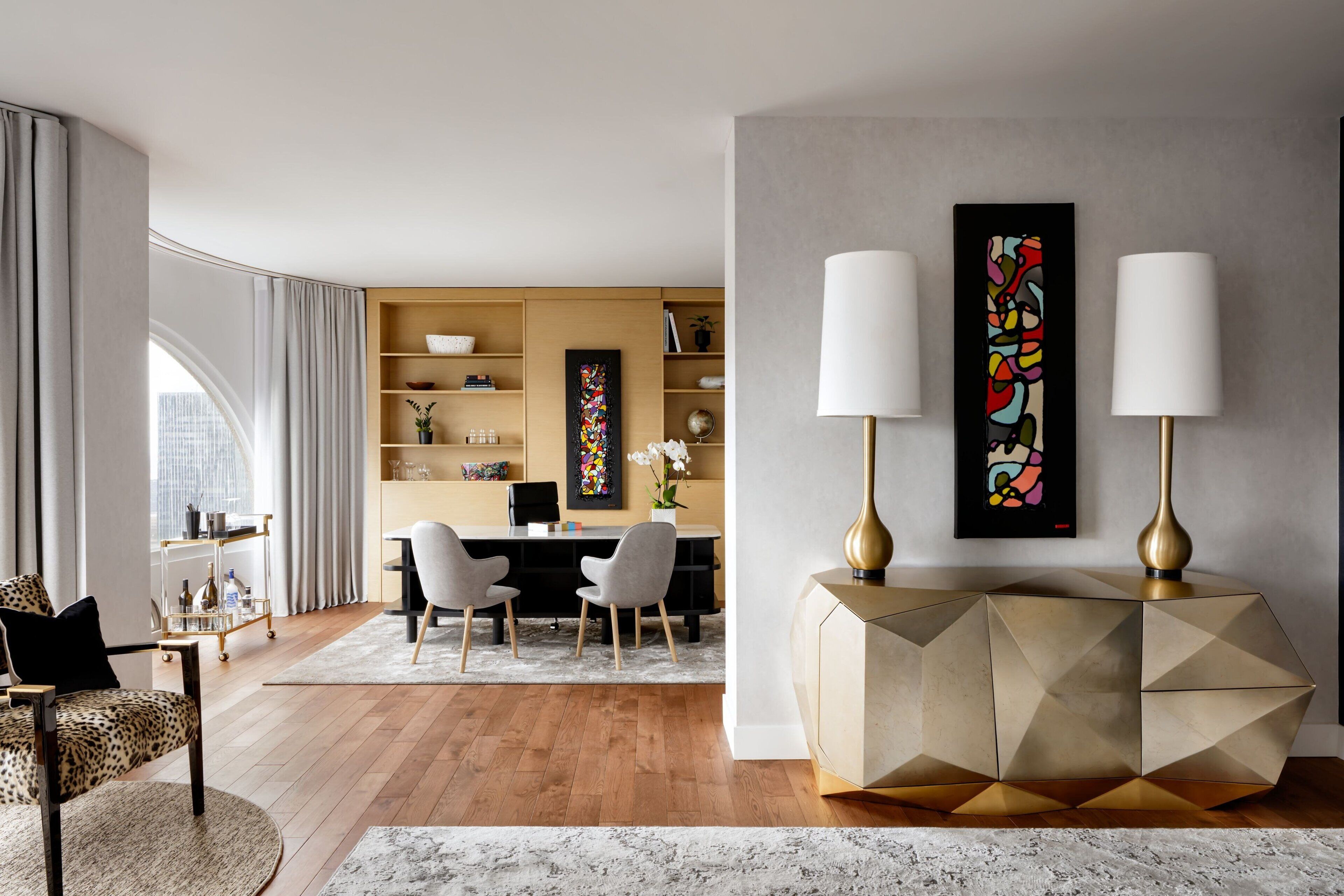 A modern living room with a geometric coffee table, a sofa, and a dining area with a desk and chairs.