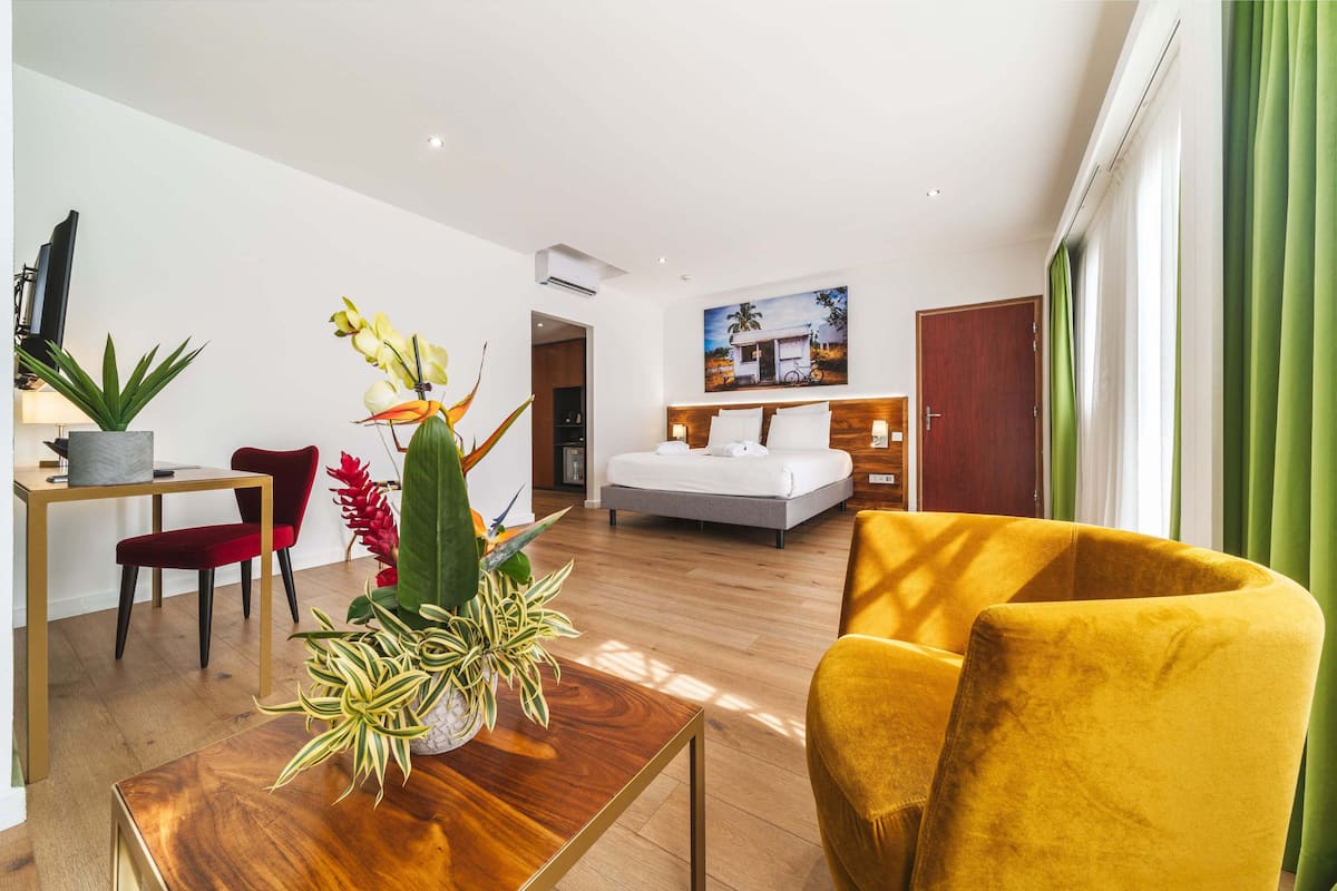 A modern hotel room with a bed, a desk, a chair, and a sofa.