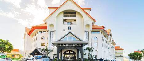 A hotel with a prominent entrance, multiple balconies, and a clear sky.